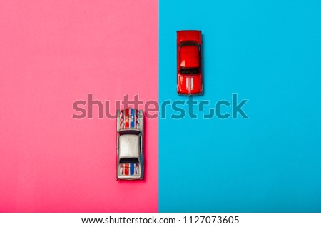 two toy cars on the background of two colors go to meet each oth
