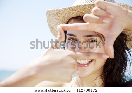 young happy female looking through a frame made from her fingers