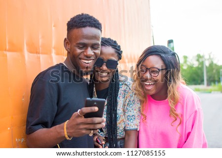 group of friends laughing over something they're viewing on a mobile phone. friends laughing together Royalty-Free Stock Photo #1127085155