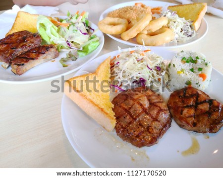 Close up Chicken ,pork , T-bone beef ,ribs steak served with french fries, soft drink ,Onion Rings and salads vegetables in cafe.Top view 
