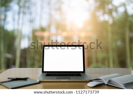 Workspace wood desk with Laptop with blank screen and wireless mouse and graphics tablet and notebook at nature blurred background at light bokeh.