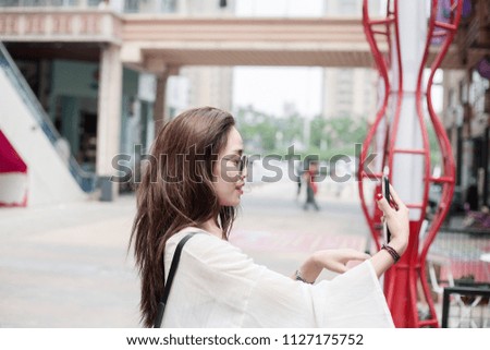 A young fashionable girl taking a selfie on her mobile phone in the city pedestrian street