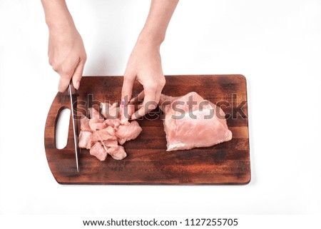 Cutting raw meat with a kitchen knife on a cutting board isolated on white background