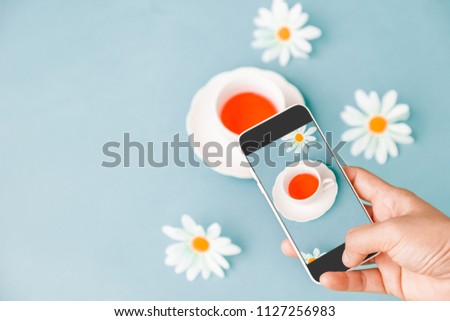 
Hands taking photo to Cup of red Tea Berry with cell telephone or smartphone digital camera for Post to Social Network and Social Media Online on the Internet . Customise pastel bright colors tone .