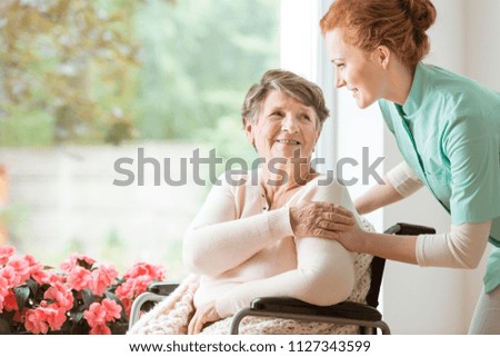 Young nurse helping an elderly woman in a wheelchair. Nursing home concept Royalty-Free Stock Photo #1127343599