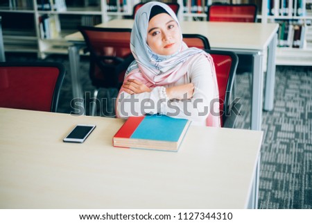 Muslim woman with a book at the library. Woman with hijab in library