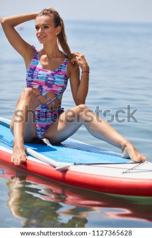 SUP Stand up paddle board woman paddle boarding on lake standing happy on paddleboard on blue water.