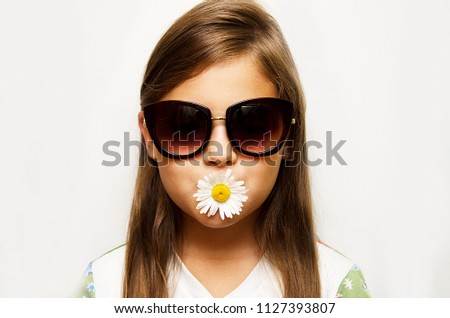 girl in sunglasses holding lips Daisy flower on white background