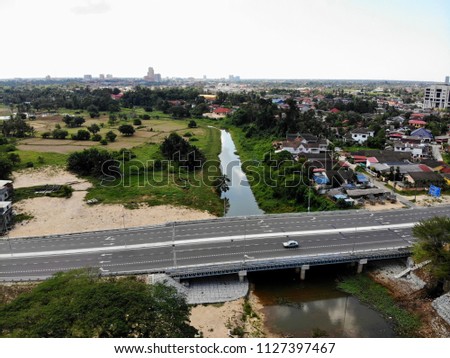 Aerial view of river and housing area during afternoon in small town in Kelantan with reflection of sky on the river. A mixed of nature and development area. 