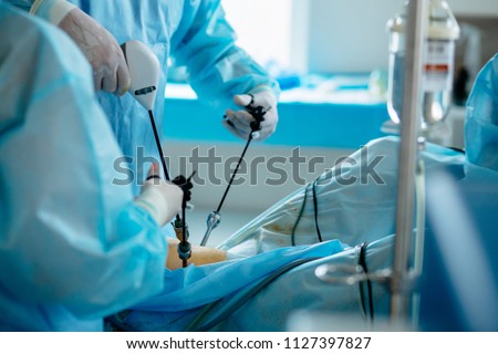 Unrecognizable surgeon's holing the instrument in abdomen of patient. The surgeon's doing laparoscopic surgery in the operating room. Minimally invasive surgery. Close up Royalty-Free Stock Photo #1127397827