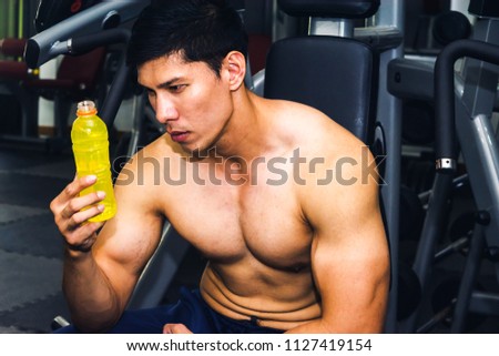 Asian man has muscle exercise in the gym.And Asian handsome muscles are tired, so drink Electrolyte drink.