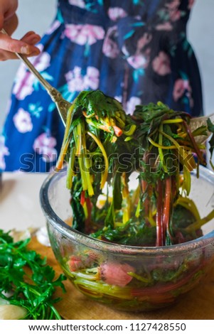 Woman hands holds with spoons cooked boiled beetroot leaves and sprouts as part of Georgian traditional food meal pkhali. Cooked as appetizer. Vegan vegetarian healthy food.