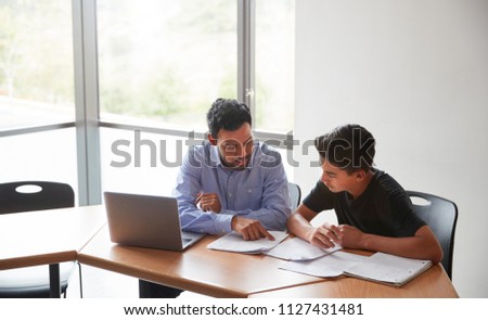 High School Tutor Giving Male Student With Laptop One To One Tuition At Desk Royalty-Free Stock Photo #1127431481