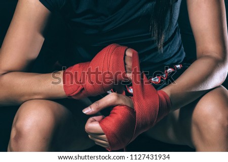 Unidentified face of woman boxer wrapping her hand in boxing arena sport. Texture effect may visible. Selective focus Royalty-Free Stock Photo #1127431934
