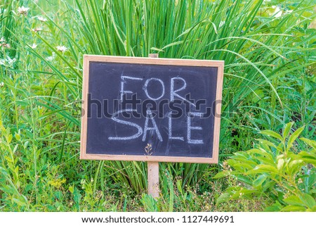 Sign board "for sale" in the meadow on sunny day