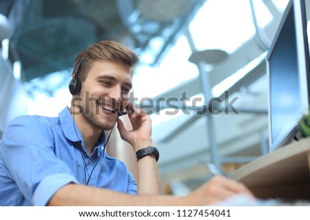 Smiling friendly handsome young male call centre operator. Royalty-Free Stock Photo #1127454041
