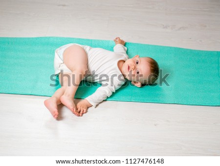 the baby is performing physical exercises on the yoga mat. Baby Yoga