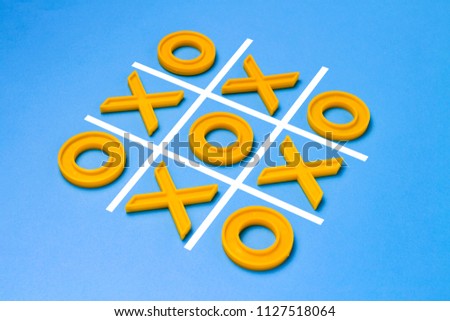 Yellow plastic crosses and a toe and a ruled field for playing tic-tac-toe on a blue background. Concept XO Win Challenge. Educational game for kids.