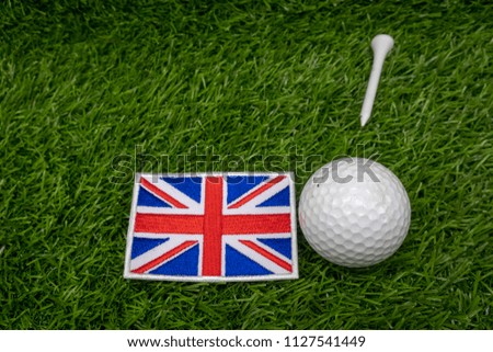 Golf ball with Union Jack flag are on green grass background