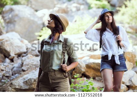 Two beautiful young girls travel in the mountains and enjoy the view of the landscape of stones.