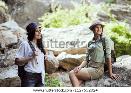 Two beautiful young girls travel in the mountains and enjoy the view of the landscape of stones.
