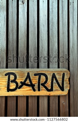 A wooden barn sign on a wooden panel wall