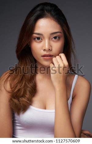 Beauty closeup profile portrait of beautiful. Cheerful girl in casual clothes posing at studio on gray background