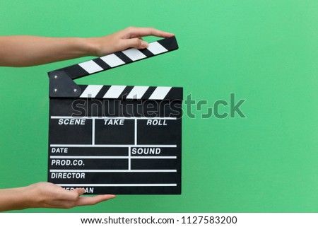 Hands take movie clapper board slate equipment film action for shouting the movie isolated on green pastel free background. copy space for add text advertisement idea. empty board for adding time line