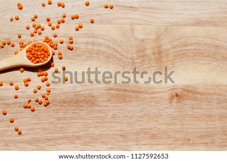 Wooden spoon with free lentil grains on wooden blackboard