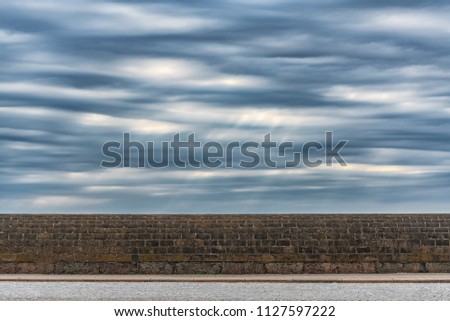 Picture of dramatic stormy sky with clouds over the stone wall.
