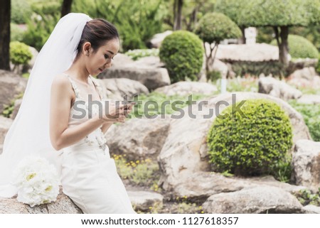 Beautiful Attractive Asian bride smile and talking with her friend in smartphone in wedding day feeling so proud and happiness