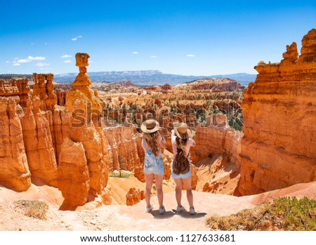 Girls on vacation hiking trip. Friends standing next to Thor's Hammer hoodoo on top of  mountain looking at beautiful view. Bryce Canyon National Park, Utah, USA Royalty-Free Stock Photo #1127633681