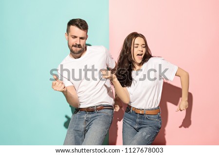 A couple of young funny and happy man and woman dancing hip-hop at studio on blue and pink trendy color background. Human emotions, youth, love and lifestyle concept Royalty-Free Stock Photo #1127678003