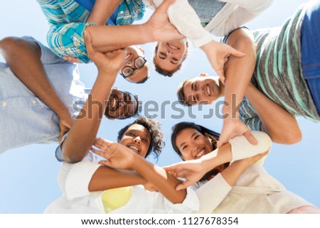 people, friendship and international concept - group of happy smiling friends outdoors standing in circle