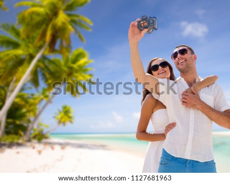 travel, tourism and summer vacation concept - smiling couple in sunglasses making selfie by digital camera over tropical beach background in french polynesia