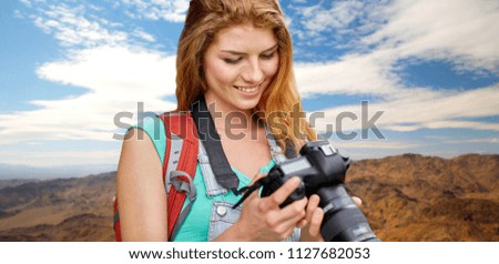 travel, tourism and photography concept - happy young woman with backpack and camera photographing over grand canyon national park hills background