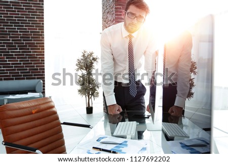 serious businessman standing near the desktop