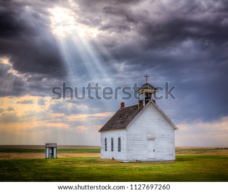 Old abandoned church at sunset with a beam of light shining down upon it. Royalty-Free Stock Photo #1127697260