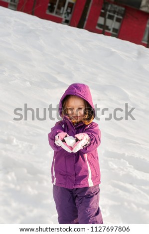 Cheerful little girl playing with snow