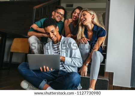 Group of friends sitting and watching something on a laptop computer Royalty-Free Stock Photo #1127730980