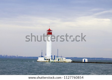 Beautiful view. The current lighthouse. Vorontsov lighthouse in Odessa against the background of the Black Sea, closeup. White tower with a red cabin at the top on a background of blue seascape