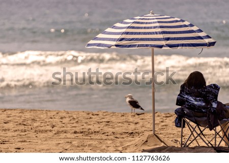 Striped beach umbrella near the ocean; selective focus.