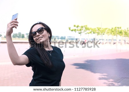 the girl makes selfie on a smartphone, on the embankment of the old city. Good summer day. Travels. Copy space.