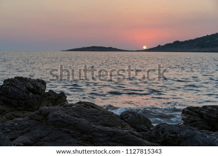 Beautiful nature and landscape photo of Adriatic Sea in Croatia.  Nice outdoors image at sunset and dusk. Rocks, stones, and water. Calm, peaceful background image of summer evening.