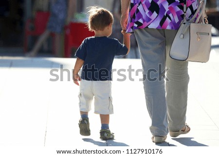 the mother holding baby's hand on the street
