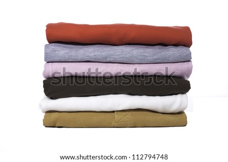 A stack of folded shirts against a white background. Royalty-Free Stock Photo #112794748