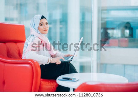 Arabic woman taking notes preparing exam and learning lessons from a book at library.