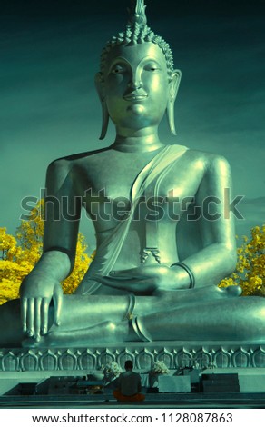 A man meditating in font of a Big Buddha Statue in thai temple from near infared style by IR mode.Paradise concept.                                     