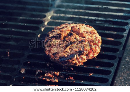 cooking burgers on hot grill with flames. Big thick Patty of ground beef with seared edges on the grill. delicious Patty