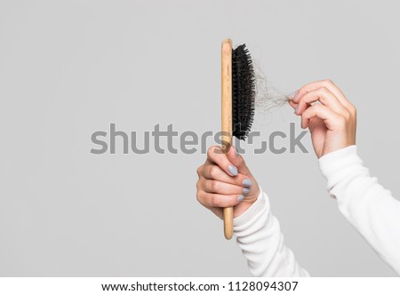 Hair loss problem, postpartum period, menstrual or endocrine disorder, hormonal disbalance, stress concept. Many hair fall after combing in hairbrush.Female untangles her hair with a comb, copy space  Royalty-Free Stock Photo #1128094307